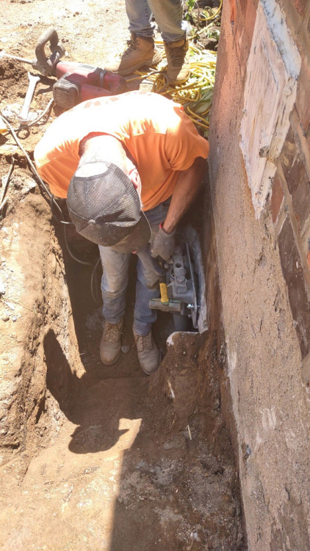 Zavza Seal Helical Pie r Installation Technician Working on Bolting a Steel Engineered ECP Foundation Bracket to the Helical Pier After Sufficient Depth Reached
