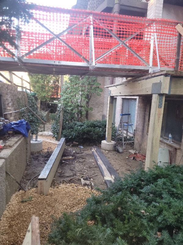 Aging timber walkway bridge demolition at condominium building face